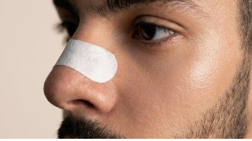Close do rosto de um homem usando a fita dilatadora nasal da Fluere sobre o nariz