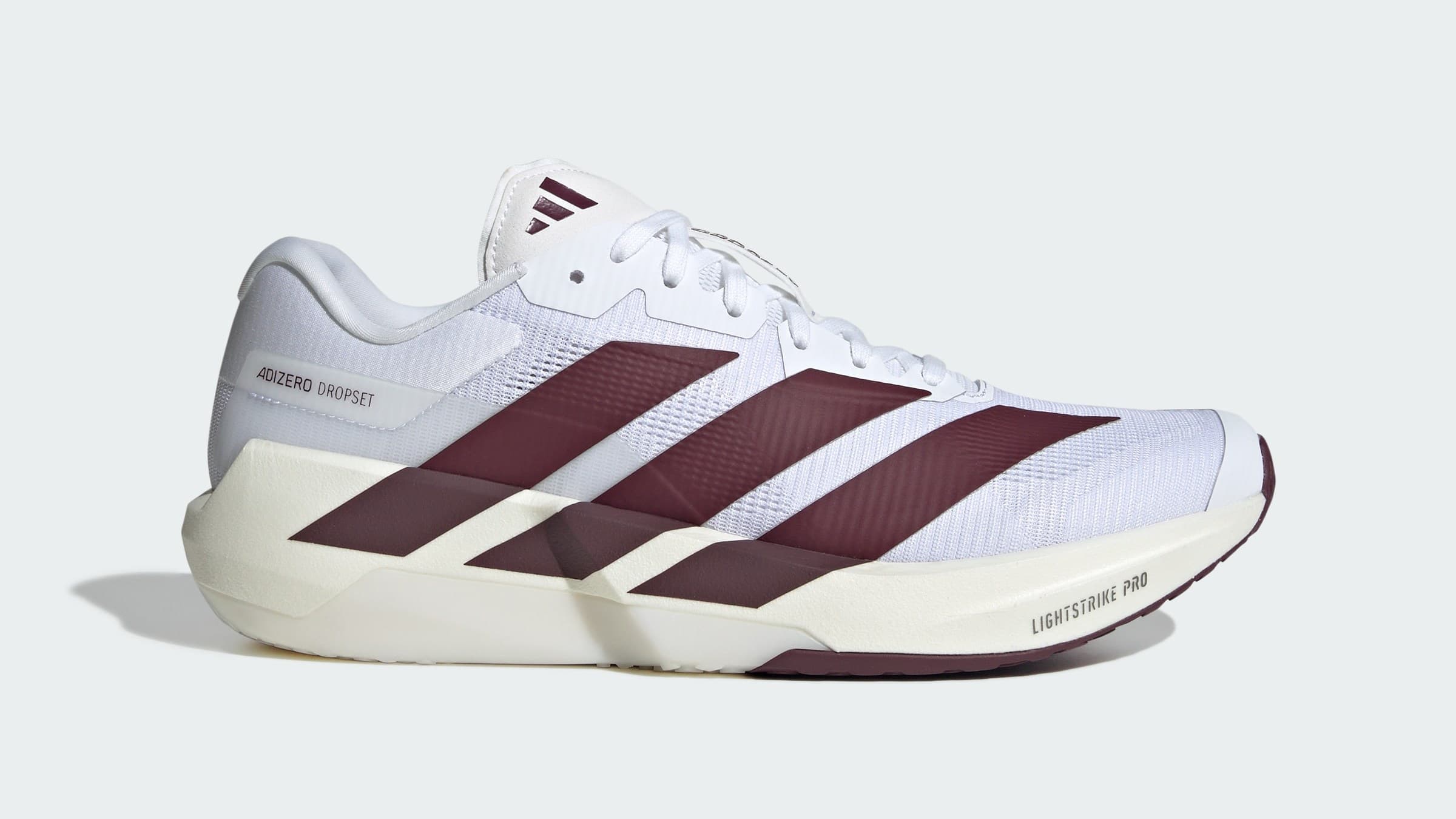 Perfil lateral do adidas Adizero Dropset Pro branco com listras vinho e entressola creme, com a inscrição Lightstrike Pro