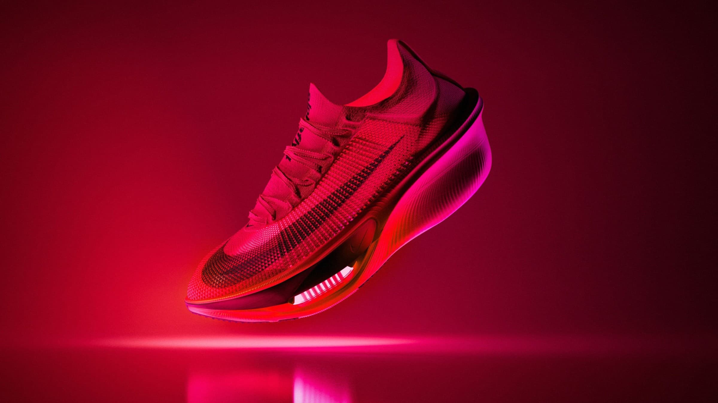 Nike Alphafly 4 suspenso no ar sob luz vermelha intensa, com a unidade Air Zoom exposta no antepé