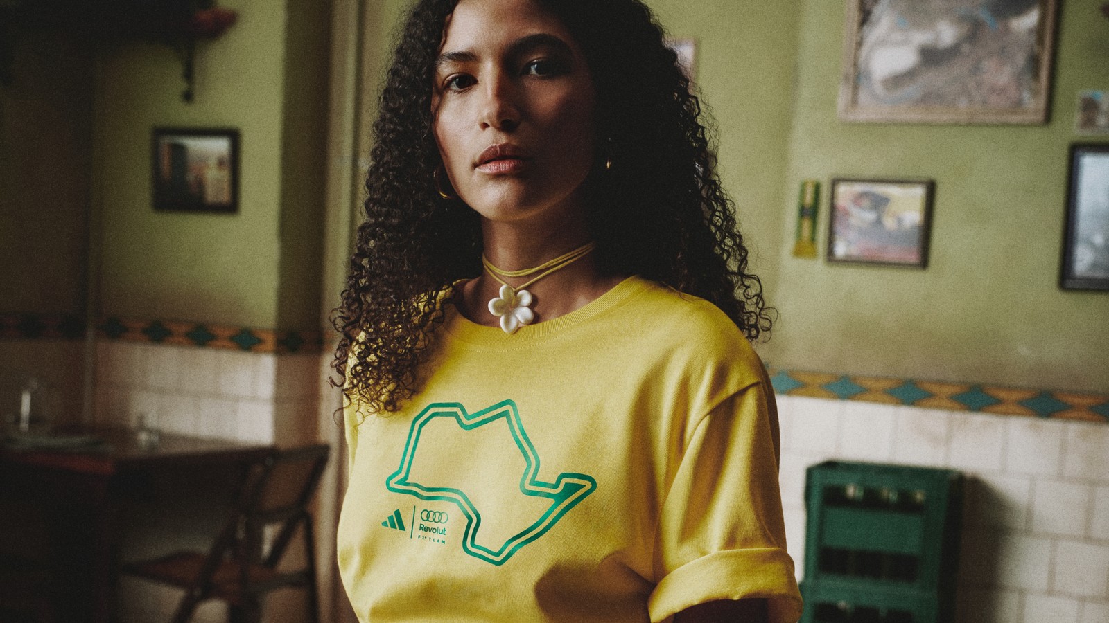 Mulher de camiseta amarela com o mapa do estado de São Paulo desenhado em verde, sentada num bar