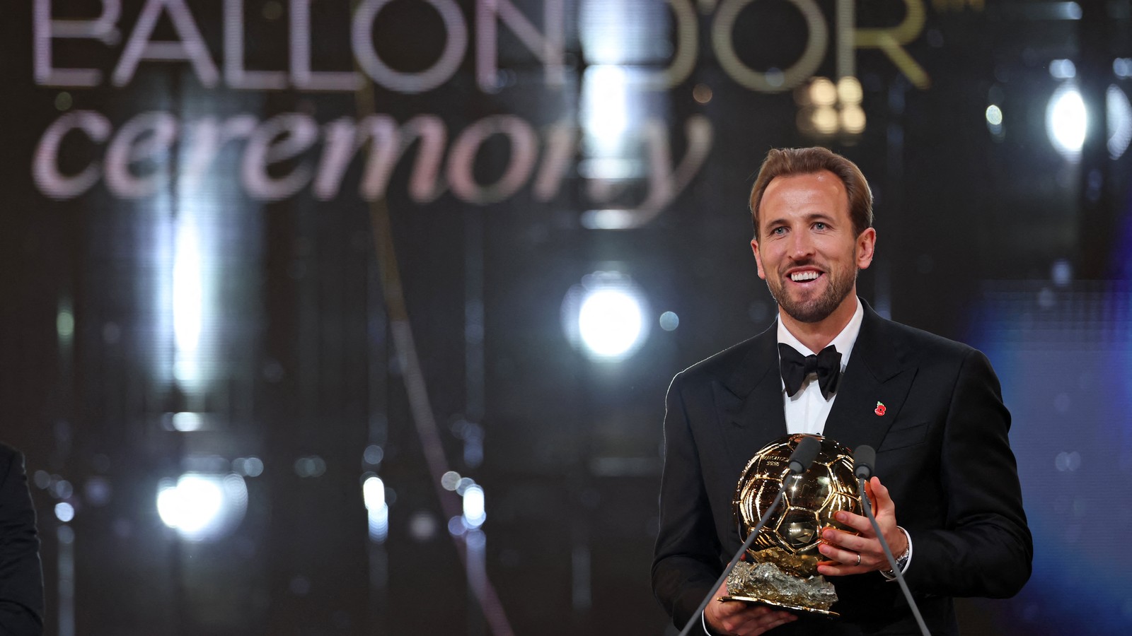Harry Kane sorri segurando o troféu da Bola de Ouro no palco do London Palladium