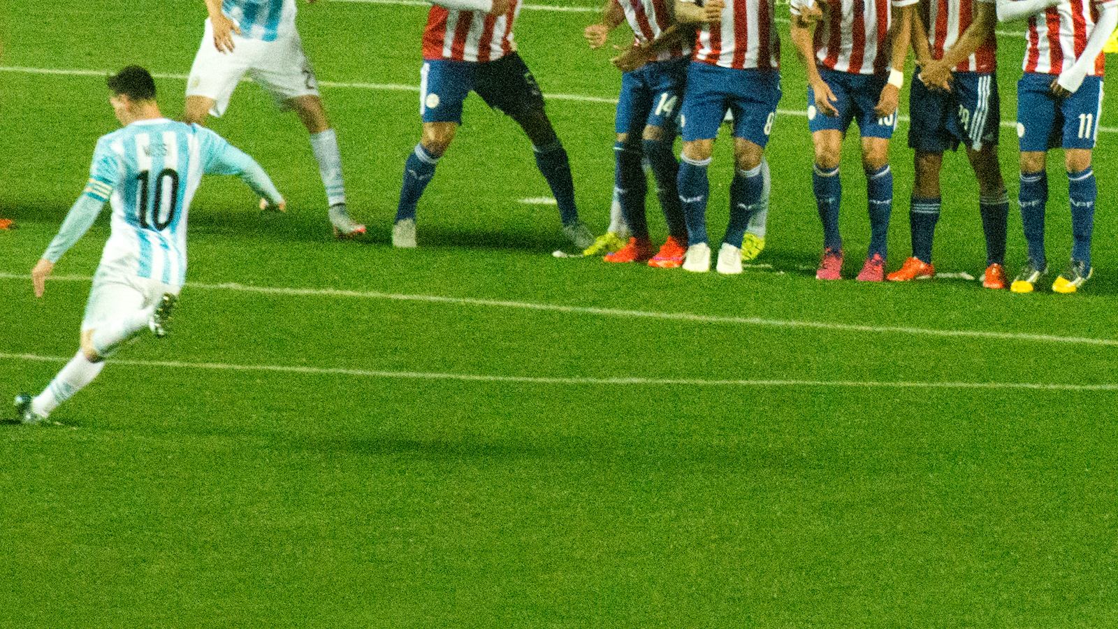 Messi cobra falta com a camisa da Argentina diante da barreira adversária, em campo iluminado à noite
