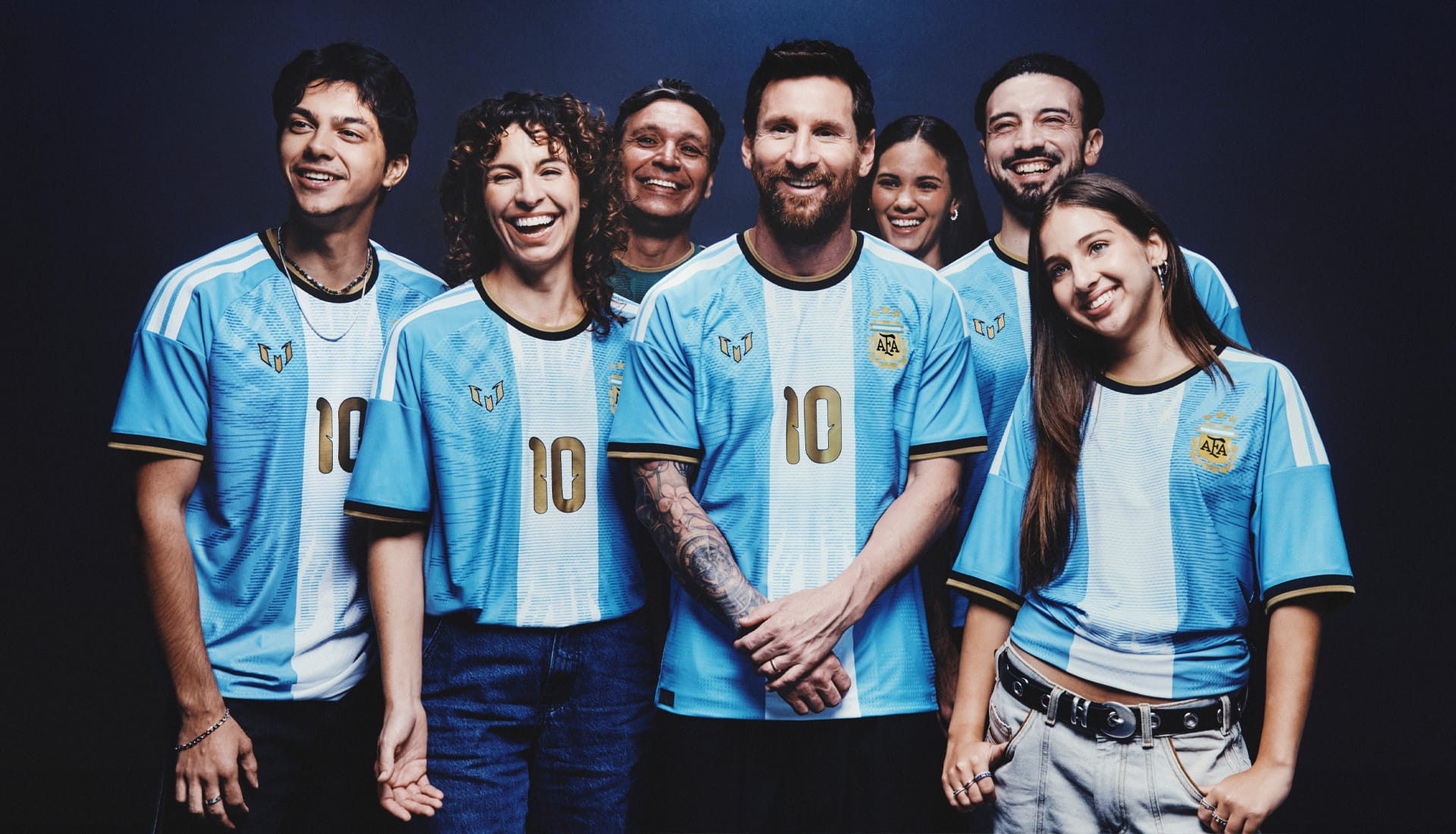 Grupo de torcedores argentinos de diferentes idades posa ao lado de Messi, todos vestindo a camisa especial de despedida com o número 10