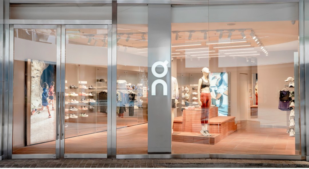 Fachada envidraçada da primeira loja da On no Brasil, no JK Iguatemi, com o logo da marca em destaque