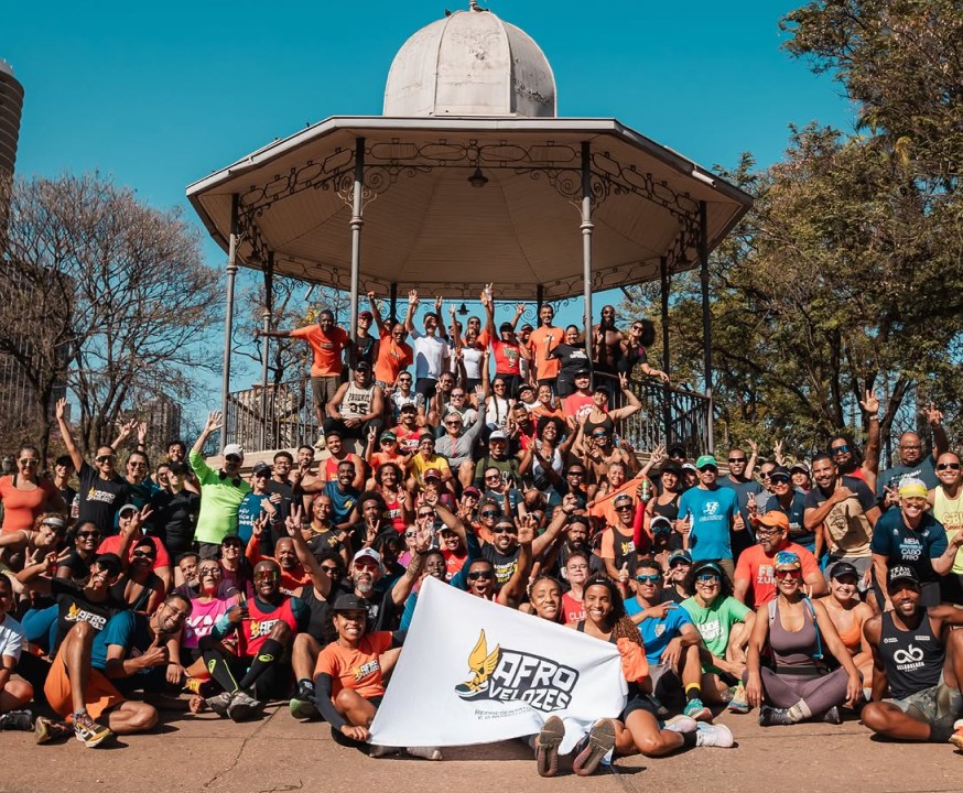 Grupo grande do Afrovelozes posa em frente a um coreto em Belo Horizonte, com a bandeira do clube