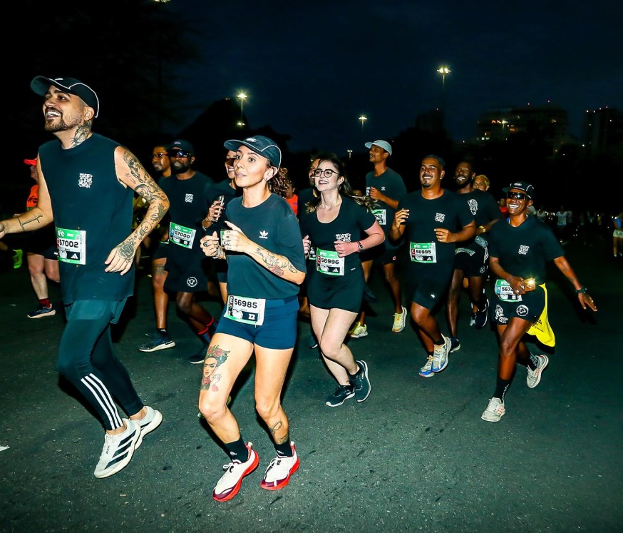 Corredores da Ghetto Run Crew correm à noite com camisetas pretas e números de peito de prova