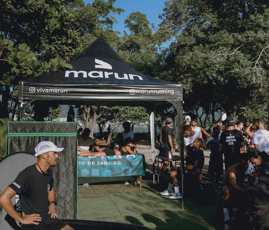 Corredores do marun running club reunidos sob a tenda do clube, à beira da Lagoa Rodrigo de Freitas