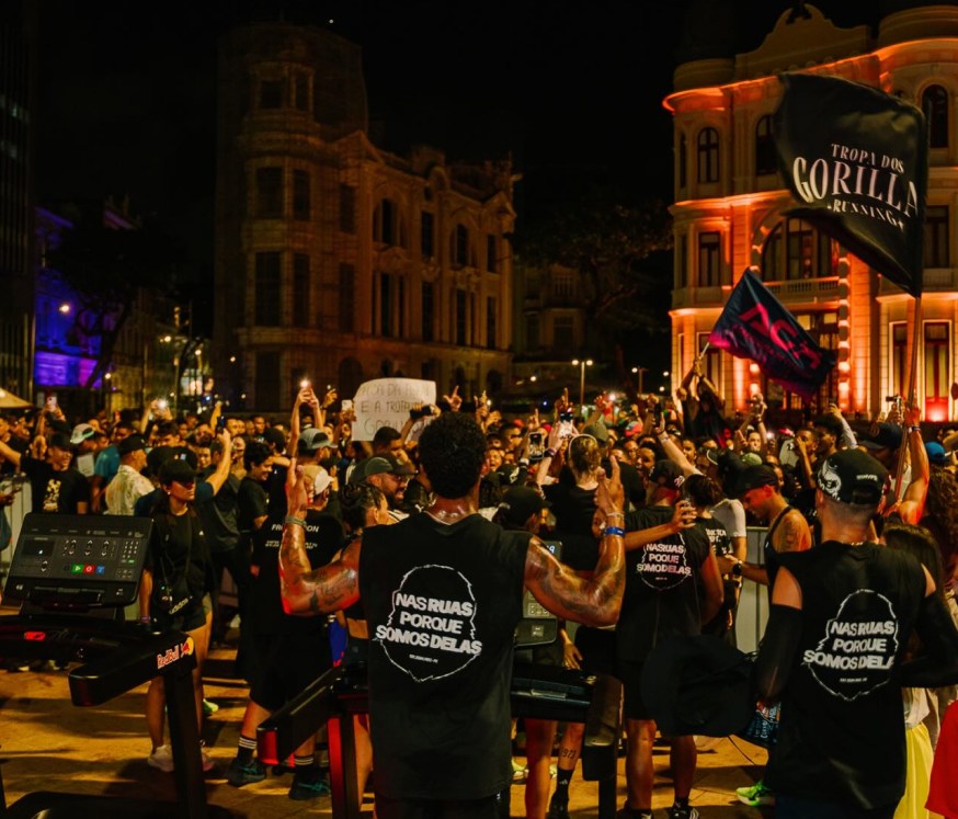 Multidão da Tropa dos Gorillas reunida à noite no Recife, com bandeiras do grupo erguidas