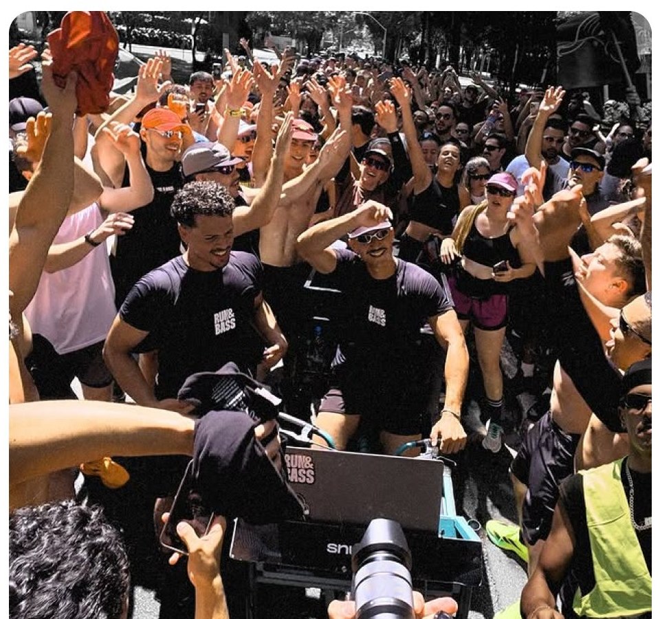 Multidão de corredores do Run&Bass com os braços erguidos em volta de uma cabine de som na rua