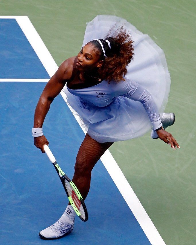 Serena Williams saca no US Open de 2018 com o vestido lilás de saia de tule desenhado por Virgil Abloh, com uma manga só e a inscrição entre aspas sobre o logo da Nike