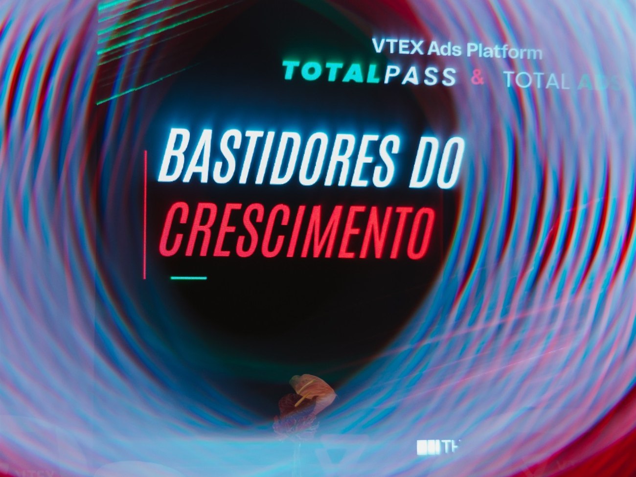 Tela do evento com o letreiro Bastidores do Crescimento, VTEX Ads Platform, TotalPass e Total Ads, registrada em longa exposição